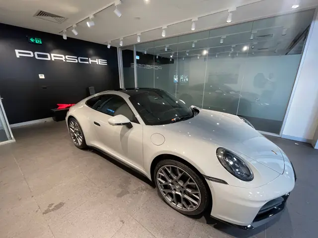 White Porsche 911 with tinted windows in a Porsche showroom