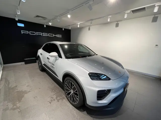 White Porsche SUV with tinted windows in a Porsche showroom