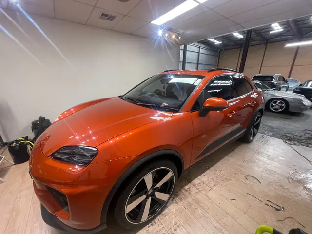 Orange Porsche SUV with tinted windows in the workshop